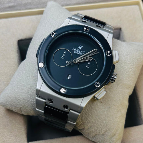 Hublot watch with a dark blue dial and silver-toned case, displayed on a beige cushion inside its presentation box.